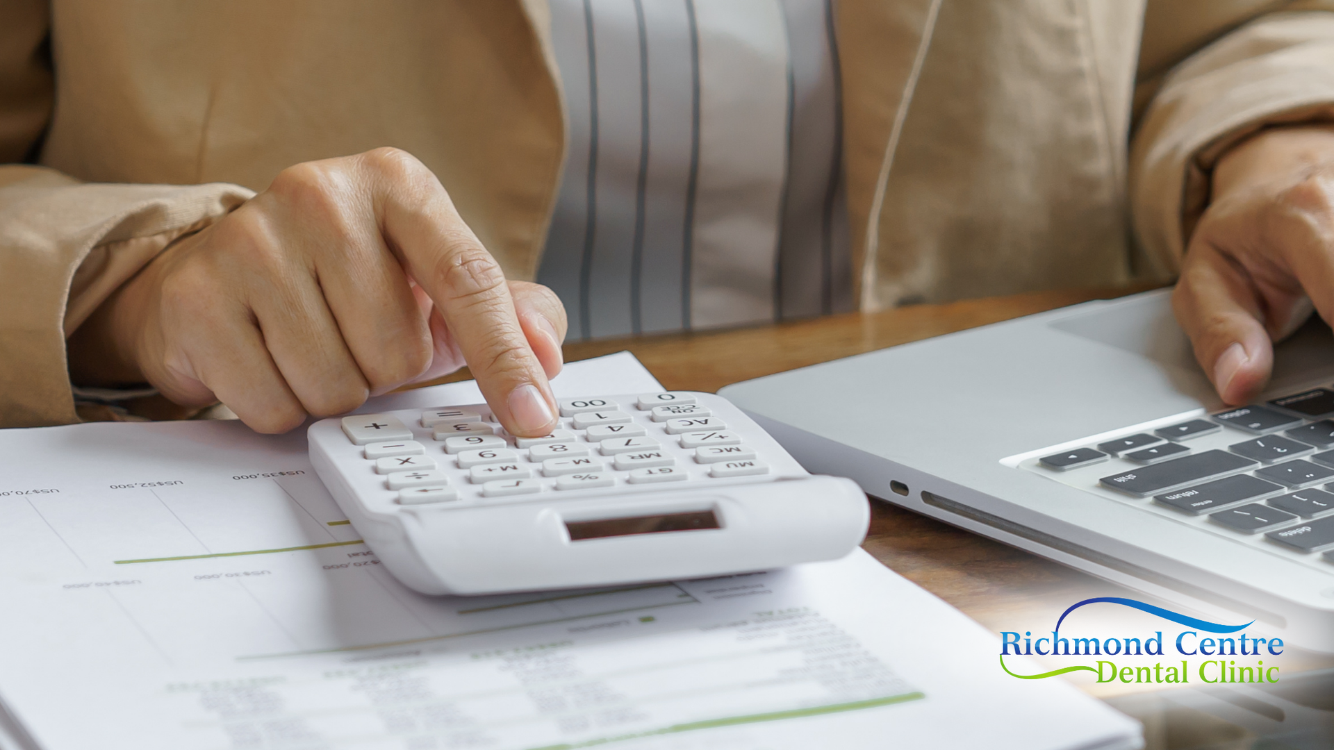 Person using a calculator and laptop, with paperwork.